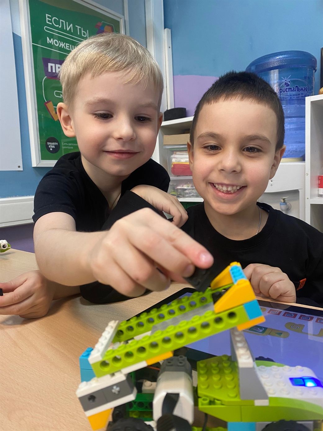 Двое учеников РобоСамары собирают робота из LEGO WeDo и программируют его на планшете